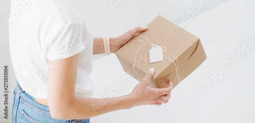 Woman in casual clothes holding postal cardboard box, checking wrappings at home