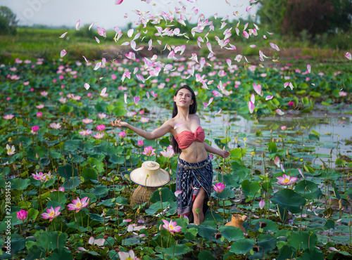 Farmer woman, portrait beautiful model in local Thai costume and sombrero in the pink lotus blooming and falling field.