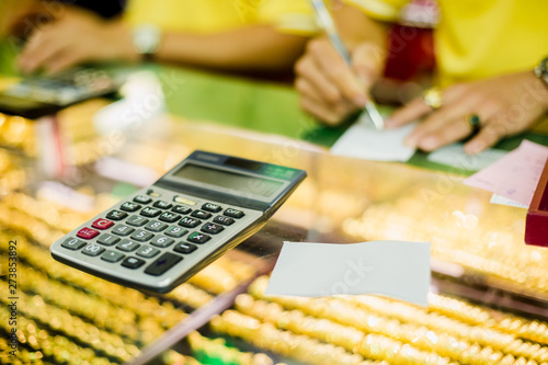the calculator to calculate the purchase of gold jewelry with blurry sale staff writing on ticket