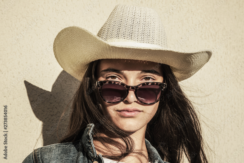 Self-confident young modern fashionable girl in sunglasses and hat with confident look from under glasses Stock-foto | Adobe Stock