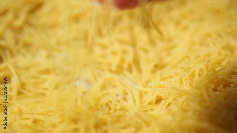 Female hand picks dry thin short noodles for cooking. Yellow noodle background. Macro. Closeup. Slow motion Female hand picks dry thin short noodles for cooking. Yellow noodle background. Macro. Closeup. Slow motion