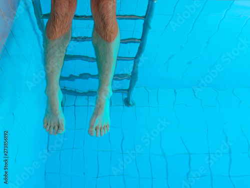 adult cuacasian man's legs underwater in swimming pool. Summer. Vacation and sport concept.
