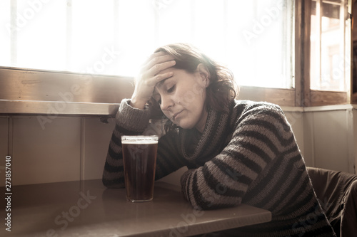 Alcoholic depressed woman drinking in a bar feeling sad hopeless