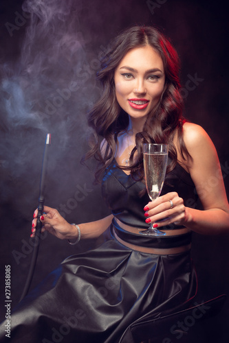 Young woman smoking a hookah on a dark background