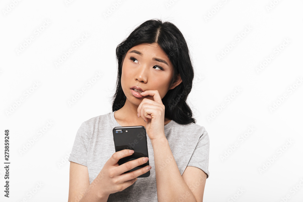 Asian beautiful young woman posing isolated over white wall background using mobile phone. Asian beautiful young woman posing isolated over white wall background using mobile phone.