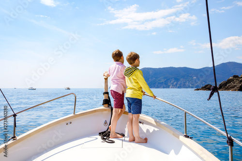 Two adorable school kid boys, best friends enjoying sailing boat trip. Family vacations on sea on sunny day. Children smiling. Brothers, schoolchilden, siblings, best friends having fun on yacht. © Irina Schmidt