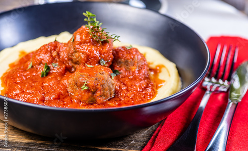Traditional meatballs in tomato sauce on a bed of mashed potato in a blue bowl
