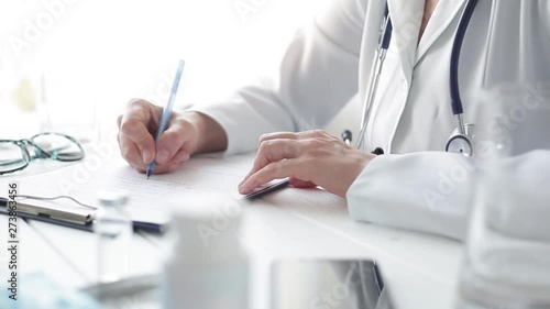 	 Woman doctor writes a medical report in the office of the clinic.