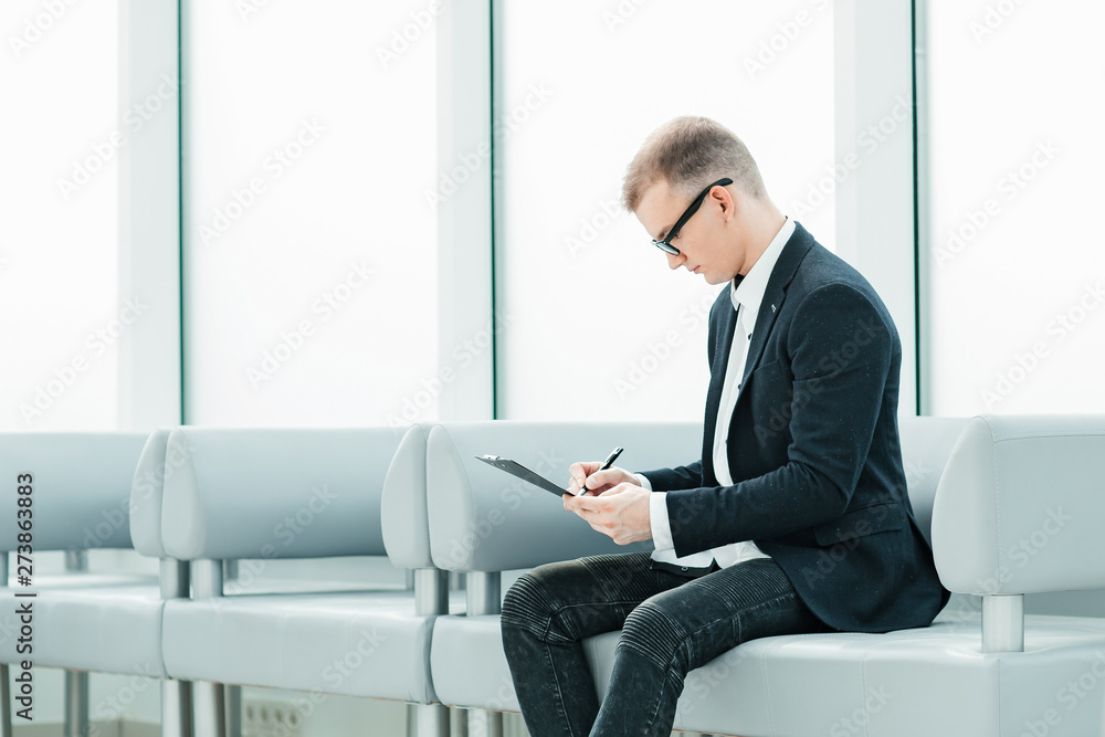 businessman reading a business document sitting in the office lobby businessman reading a business document sitting in the office lobby