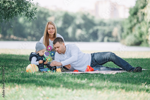 parents play with their little son sitting on the grass