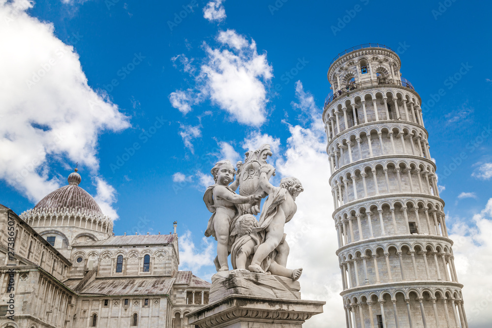 The Leaning Tower of Pisa, the statue of Putti Fountain and cathedral in Square of Miracles at sunny day, Tuscany region, Italy.