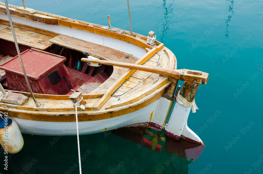 Back of an old wooden boat with a steering handle and propeller.