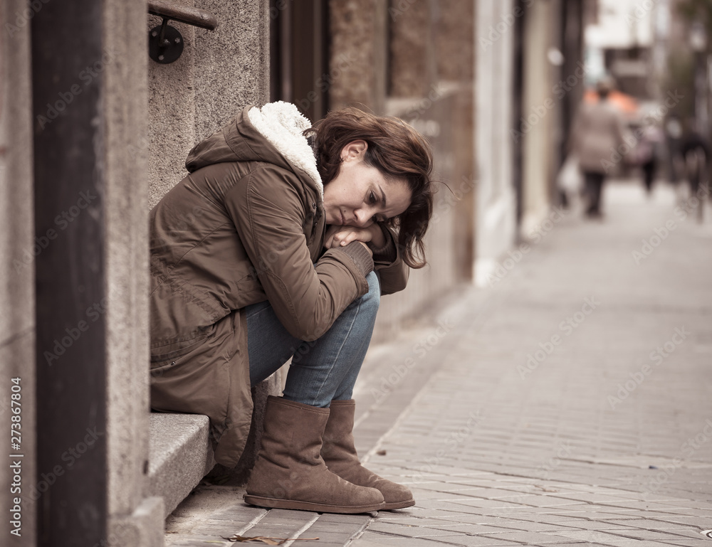 Depressed young woman sitting on urban city street overwhelmed a Depressed young woman sitting on urban city street overwhelmed a