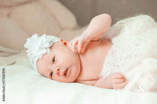 newborn baby girl in a beautiful bonnet lying on a blanket.
