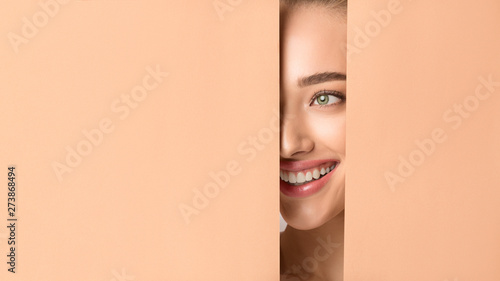 Woman With Nude Makeup Peering Into Hole In Peach Paper photo