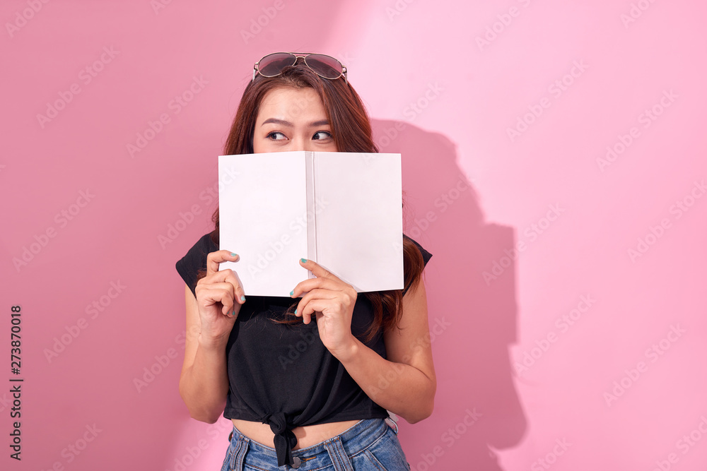 Fototapeta premium Image of beautiful young pretty woman posing isolated over pink background wall holding book reading.