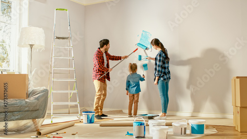 Φωτογραφία Beautiful Young Family are Showing How to Paint Walls to Their Adorable Small Daughter