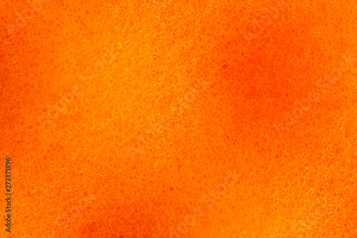 Orange abstract background and porous surface pattern with light and dark patches. Nanostructure and molecular composition of the material sponge for washing dishes. Image under the microscope, macro.