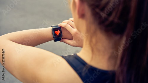 Young woman checking the sports watch measuring heart rate and performance after running.