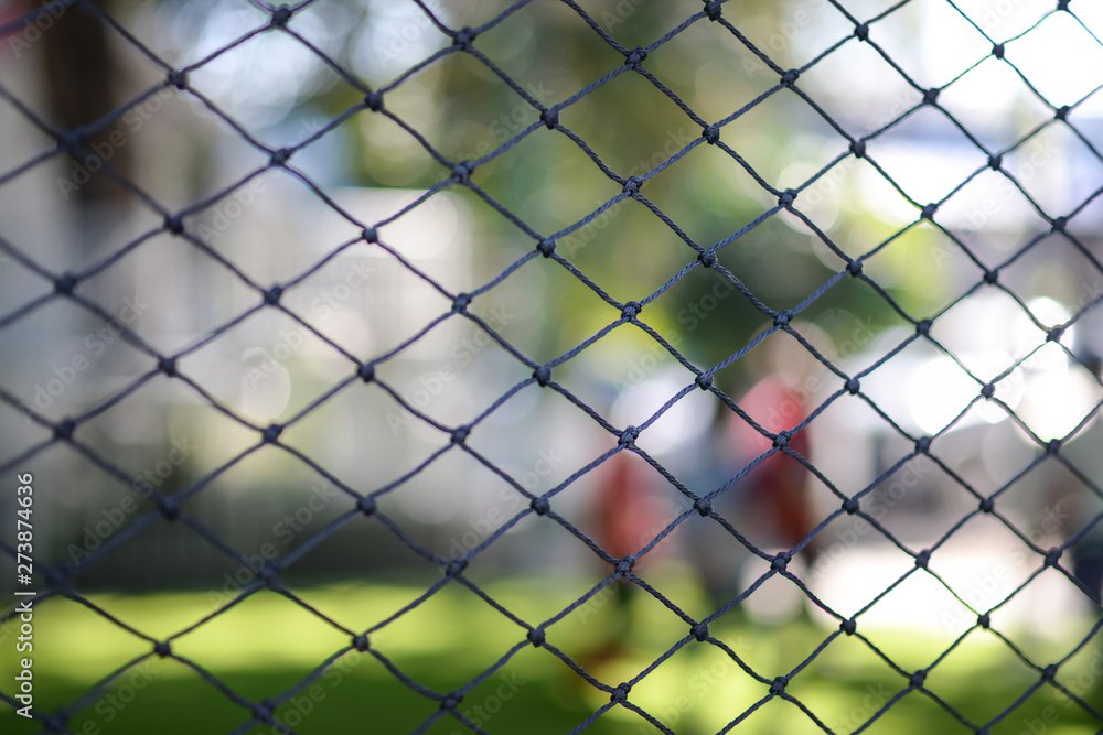 Looking through a net.Selective focus on a football net with blur background.A stretched net with people in the background. Looking through a net.Selective focus on a football net with blur background.A stretched net with people in the background.