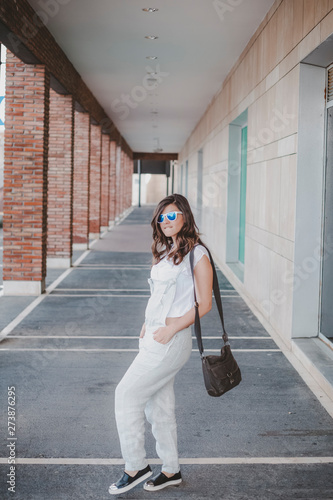 woman with overalls and sunglasses posing in a gallery