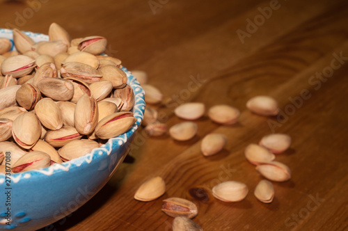Pistachios in the bowl on the wooden table