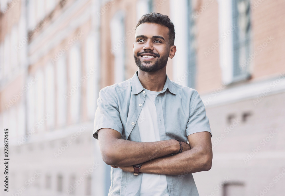 © kite_rin - Portrait of handsome smiling young man with folded arms. Laughing joyful cheerful men with crossed hands in a city