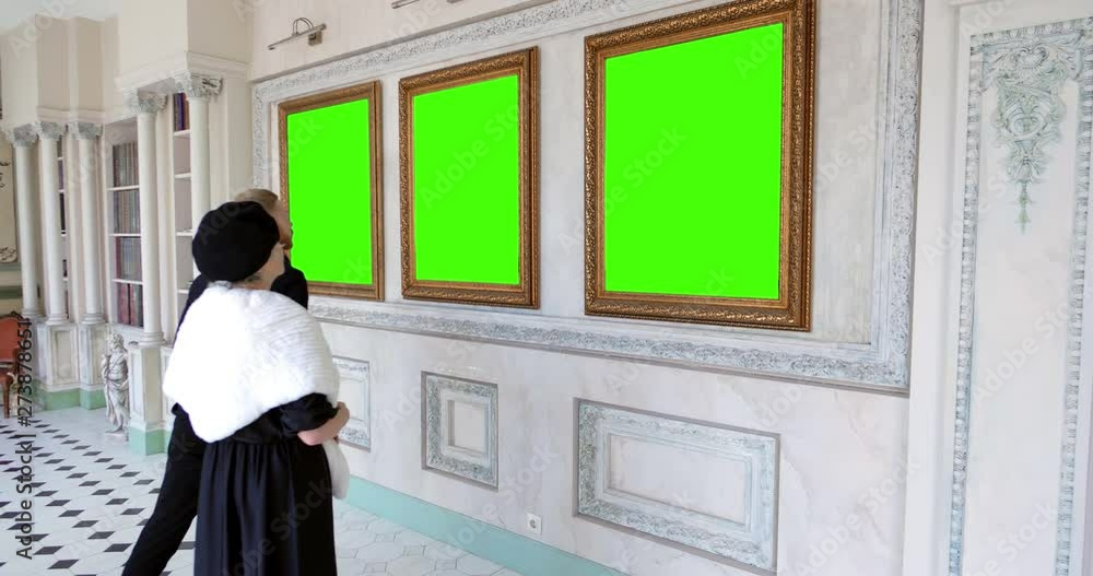 Elderly mother and adult son looking at paintings in museum Elderly mother and adult son looking at paintings in museum