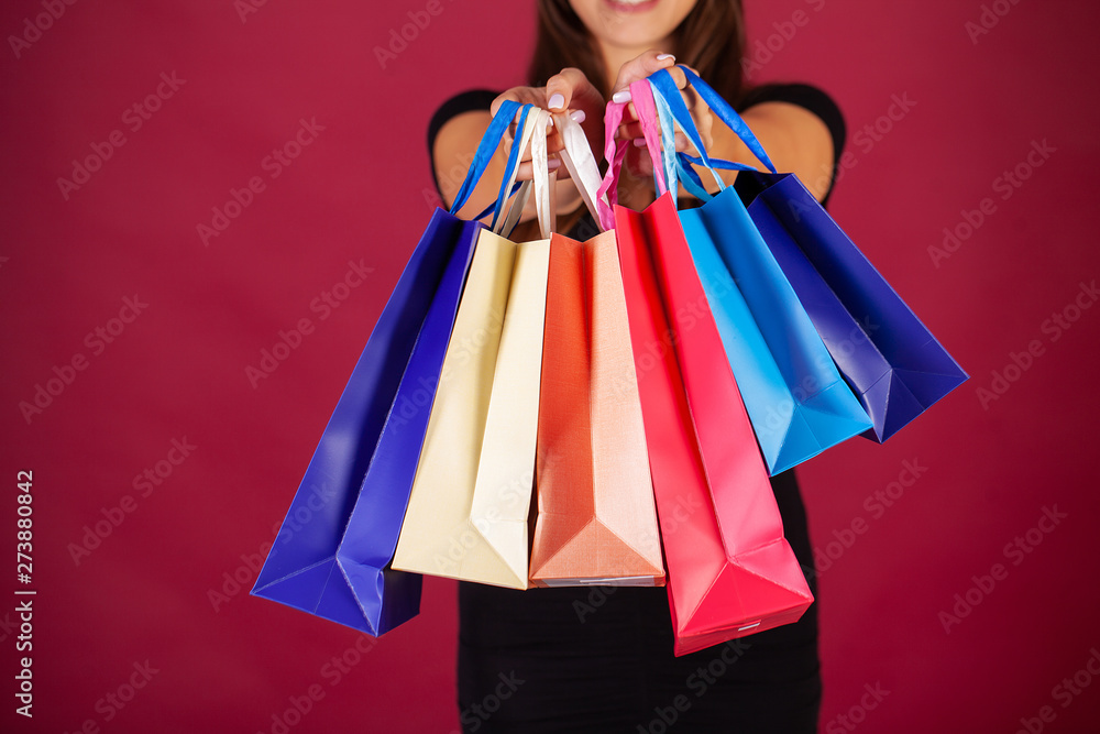 Shopping. Woman holding colored bags on red background in black friday holiday