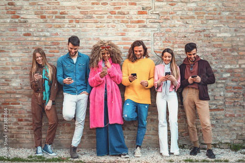 Multiracial friends using smartphone against an ancient wall - Young people addicted by mobile smart phone - Technology concept with always connected . using social media. Filtered image