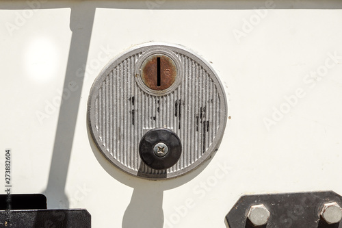 A closeup of a metal coin slot panel from a coin operated machine with entry and exit slots