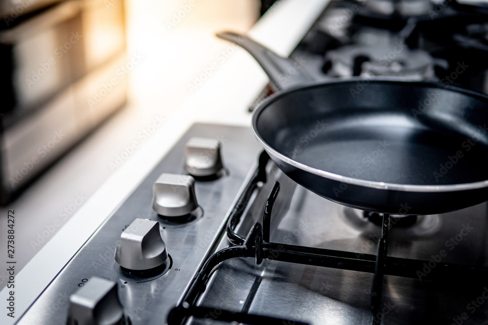Black Teflon pan on modern gas stove in the kitchen. Cookware or kitchenware concepts Black Teflon pan on modern gas stove in the kitchen. Cookware or kitchenware concepts