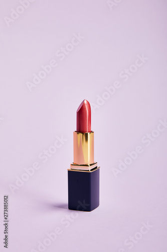 single opened tube of red lipstick on purple photo