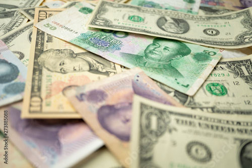 US dollar stack and Chinese yuan banknotes on the table The concept of a trade war between the United States and China