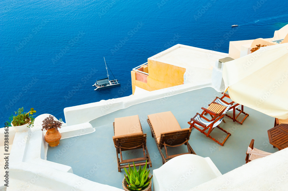 Chaise lounges on the terrace with sea view. Santorini island, Greece. Travel and vacation concept