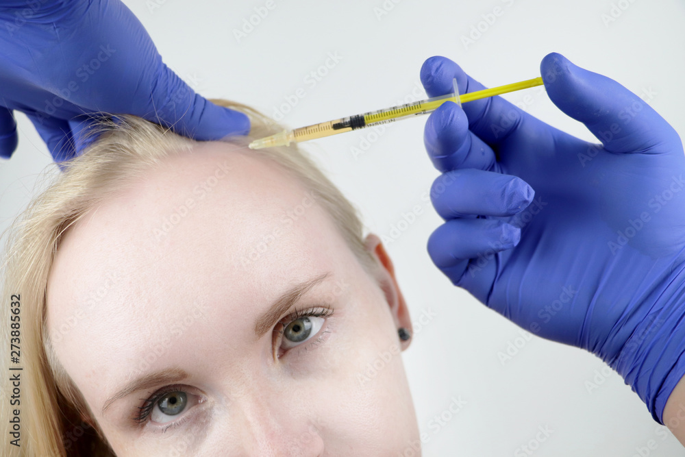 Hair mesotherapy or hair transplant: a beautician doctor makes injections in the head of a woman for hair growth or to prevent baldness Hair mesotherapy or hair transplant: a beautician doctor makes injections in the head of a woman for hair growth or to prevent baldness
