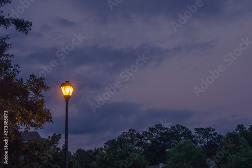 Single lone street light lamp post at night shining in the dark in the evening