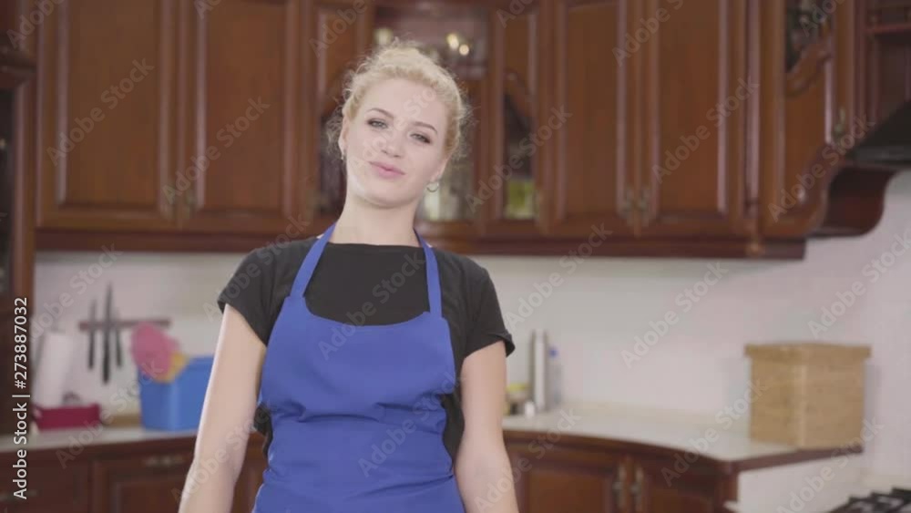 Portrait young beautiful woman standing on the kitchen with crossed hands holding bottles of detergent, looking in the camera smiling. Positive female housekeeper cleaning her home. The concept of Portrait young beautiful woman standing on the kitchen with crossed hands holding bottles of detergent, looking in the camera smiling. Positive female housekeeper cleaning her home. The concept of
