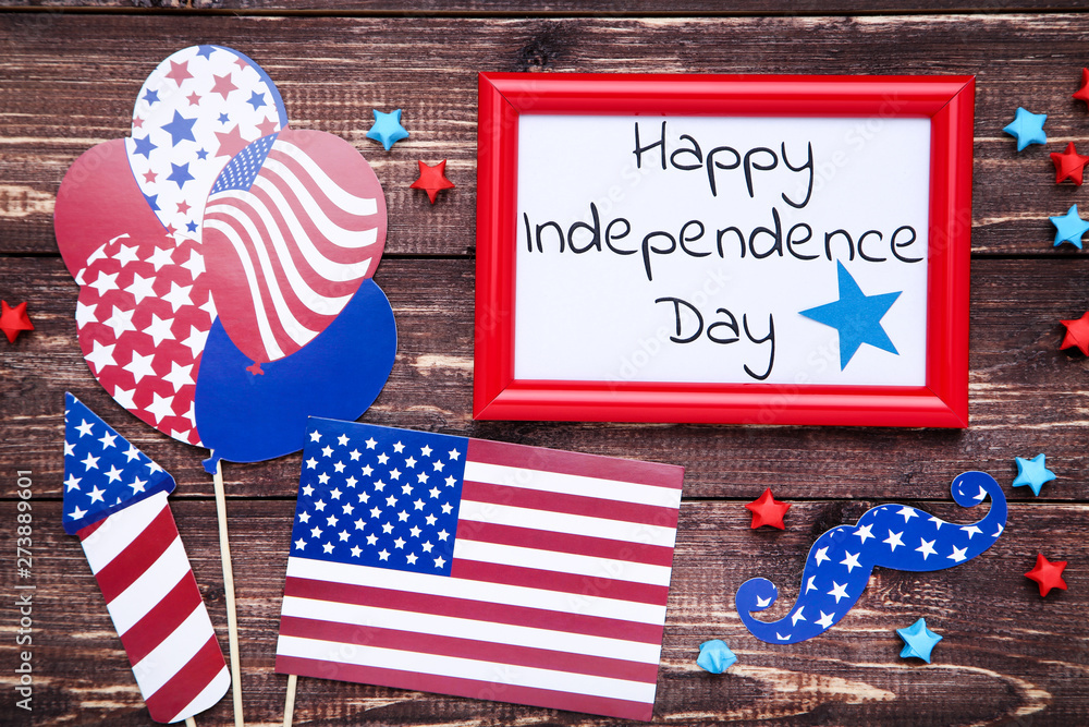 Obraz premium Text Happy Independence Day with paper flag, stars and balloons on brown wooden table