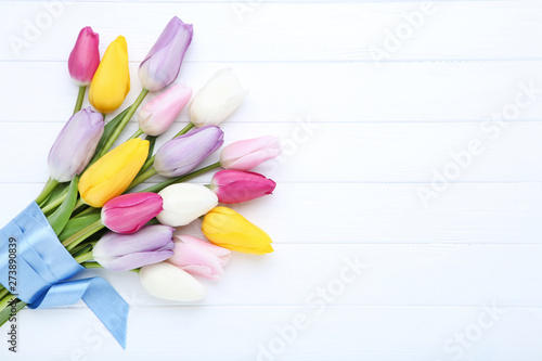Bouquet of tulip flowers with ribbon on white wooden table