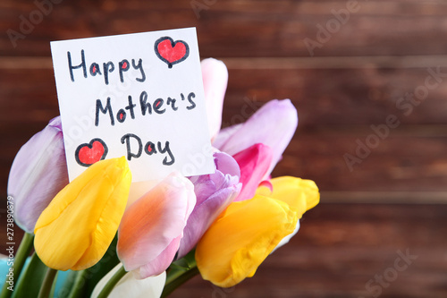Bouquet of tulip flowers with text Happy Mothers Day on brown background