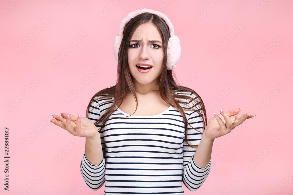 Beautiful young woman with warm headphones on pink background Beautiful young woman with warm headphones on pink background