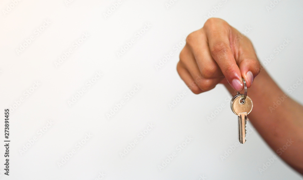 close up young asian man hand holding house's key on white background with copyspace for design of home loan concept close up young asian man hand holding house's key on white background with copyspace for design of home loan concept