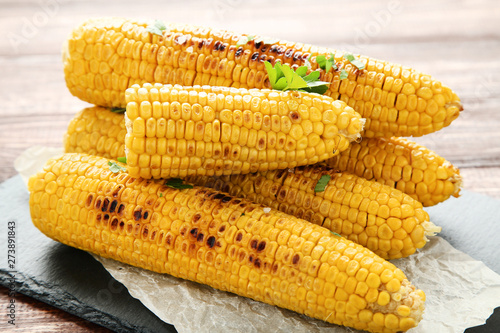Grilled corn with green parsley on wooden table