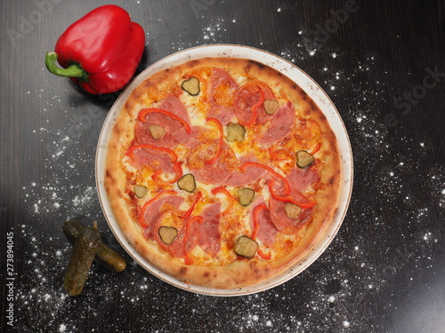 Pizza with sausage, pepper and pickled cucumbers on a plate
