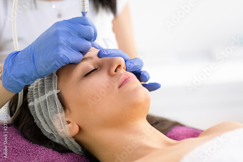 Beautician treating male face by cavitation.