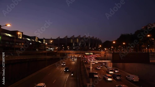 Paris, France - April 6, 2019: Car Traffic by night at Paris Parc Des Princes soccer stadium taken from bridge view. Lights, cars, fires, trees, bus, parisian monument, blur effect. Lot of vehicles. photo