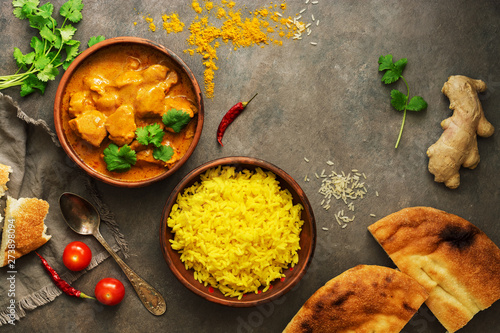Chicken tikka masala with yellow rice and naan on a dark brown background. Indian food. Top view, copy space, flat lay.