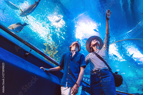 Fototapet Son with his Mother watching underwater sea inhabitants in huge aquarium tunnel,