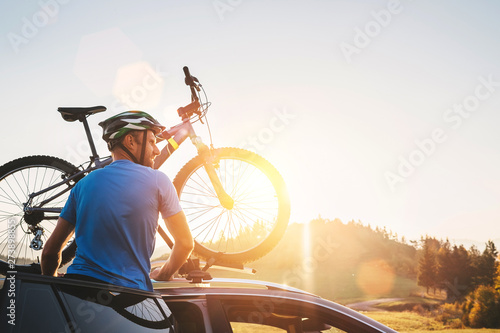 Man taking his bicycle from car roof. Mountain biking concept